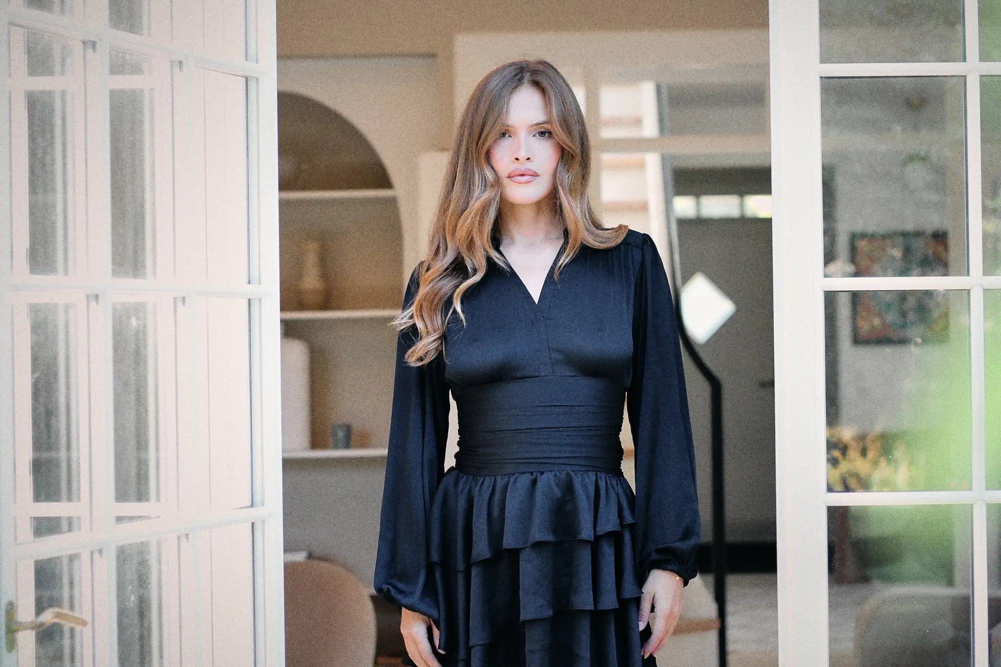 Svart fløyelskjole med volangkant og lange ermer.